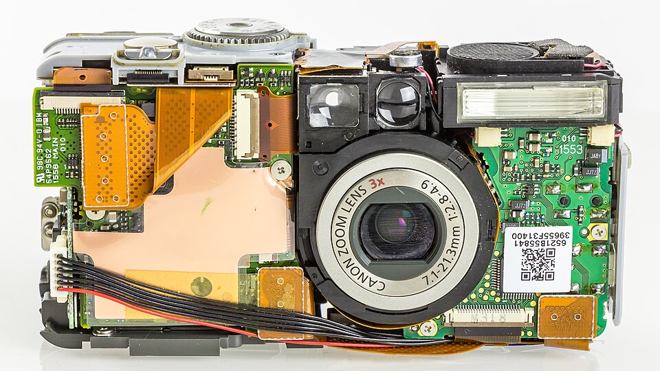 Kompaktinis fotoaparatas Canon PowerShot S45 su nuimtu korpuso dangteliu – vidinis mechanizmas